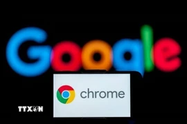 Biểu tượng Chrome trên màn hình điện thoại và biểu tượng Google (phía sau). (Ảnh: Getty Images/TTXVN)