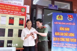 Tình nguyện viên Đội hình tình nguyện Công an tỉnh Đắk Lắk hỗ trợ người dân thực hiện thủ tục hành chính và thao tác cơ bản trên thiết bị điện thoại. (Ảnh: Hoài Thu/TTXVN)
