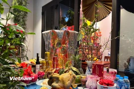 Lễ vật gà ngậm hoa hồng đỏ trong mâm cỗ cúng đêm Giao thừa. (Ảnh: Vietnam+)