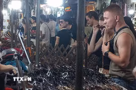Khách quốc tế yêu thích việc mua sắm quà lưu niệm tại chợ đêm phố cổ Hà Nội. (Ảnh: Tuyết Mai/TTXVN)