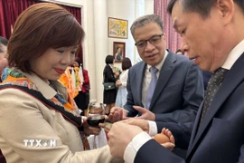 Phong tục buộc chỉ cổ tay để chúc mừng Năm mới trong Tết Bunpimay của Lào. (Ảnh: Tâm Hằng/TTXVN)