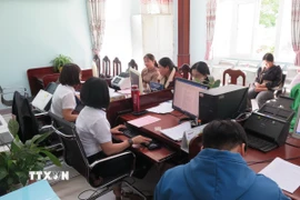 Các cán bộ Trung tâm phục vụ Hành chính công xã Bờ Y giải quyết thủ tục cho người dân. (Ảnh: Dư Toán/TTXVN)