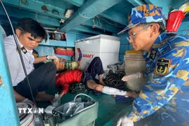 Tổ Quân y xử lý, băng nẹp cố định chân gãy cho ngư dân. (Ảnh: TTXVN phát)