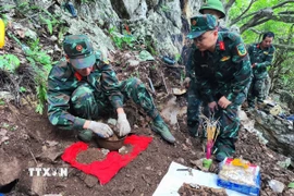 Trung tá Nguyễn Trung Kiên, Phó Chủ nhiệm Chính trị, Bộ Chỉ huy Quân sự tỉnh Hà Giang, trực tiếp chỉ đạo cất bốc 4 bộ hài cốt liệt sỹ vừa được tìm thấy tại khu vực Điểm cao 211. (Ảnh: TTXVN phát)