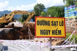 Các đơn vị chức năng cắm cảnh báo nguy hiểm do tình trạng sụt lún tại Km27+120 - Km27+200 trên quốc lộ 4D ở Lai Châu. (Ảnh: Quý Trung/TTXVN)