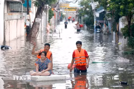 Lực lượng chức năng hỗ trợ người dân những khu vực ngập sâu di dời đến nơi ở khác. (Ảnh: Nguyễn Thanh/TTXVN)