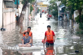 Lực lượng chức năng hỗ trợ người dân những khu vực ngập sâu di dời đến nơi ở khác. (Ảnh: Nguyễn Thanh/TTXVN)