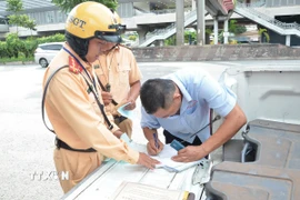 Cảnh sát giao thông lập biên bản một trường hợp tài xế xe khách vi phạm. (Ảnh: Linh Sơn/TTXVN)