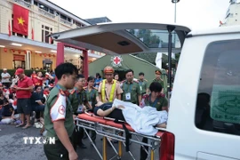 Lực lượng chức năng hỗ trợ chăm sóc sức khỏe một người dân bị ngất trên phố Lê Duẩn ngày 30/8. (Ảnh: Trần Việt/TTXVN)