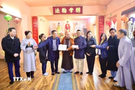 Thượng tọa Thích Pháp Nhẫn xúc động trao số tiền ủng hộ 2.000 euro của các phật tử chùa Phổ Đà cho ông Quang Anh (đứng bên phải), Phó Chủ tịch Liên hiệp hội người Việt tại CHLB Đức. (Ảnh: Phương Hoa/TTXVN)