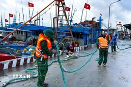 Cán bộ, chiến sỹ Đồn Biên phòng cửa khẩu cảng Cửa Lò - Bến Thuỷ (Bộ đội Biên phòng tỉnh Nghệ An) hỗ trợ ngư dân thu dọn ngư lưới cụ. (Ảnh: TTXVN phát)