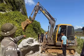 Lực lượng chức năng di chuyển tảng đá lớn ra khỏi đường ray, khẩn trương thông tuyến. (Ảnh: Nguyên Linh/TTXVN)