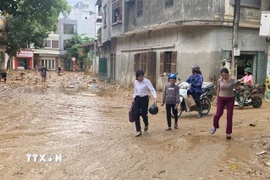 Người dân trở về nhà sau khi sơ tán tránh lũ. (Ảnh: TTXVN)