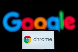 Biểu tượng Chrome trên màn hình điện thoại và biểu tượng Google (phía sau). (Ảnh: Getty Images/TTXVN)