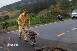 Lực lượng chức năng tiến hành lấp các hố sụt, đặt biển cảnh báo để đảm bảo an toàn. (Ảnh: TTXVN phát)