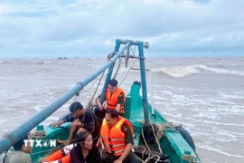 Hai ngư dân gặp nạn được tổ công tác Đồn Biên phòng Khánh Hội cứu đưa lên tàu an toàn. (Ảnh: TTXVN phát)