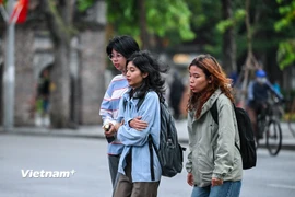 Những vị khách du lịch co ro trong trời lạnh vào sáng sớm ở Thủ đô. (Ảnh: Minh Sơn/Vietnam+)