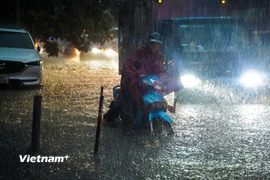 Người dân chật vật di chuyển qua các điểm ngập úng. (Ảnh: Hoài Nam/Vietnam+)