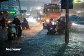 Người dân chật vật di chuyển qua các điểm ngập úng. (Ảnh: Hoài Nam/Vietnam+)