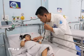 Bác sỹ Bệnh viện Nhi đồng 1 Thành phố Hồ Chí Minh, khám cho bệnh nhi mắc tay chân miệng. (Ảnh: Đinh Hằng/TTXVN)
