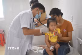 Bác sỹ khám cho bệnh nhân mắc bệnh tay chân miệng. (Ảnh: TTXVN)