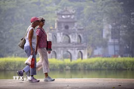 Du khách nước ngoài đi dạo bên hồ Hoàn Kiếm. (Ảnh: Tuấn Đức/TTXVN)