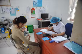Nhân viên y tế khám sàng lọc, kiểm tra tình trạng của trẻ trước khi tiêm vaccine. (Ảnh: Vũ Quang/TTXVN)