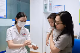Phụ huynh đưa trẻ đi tiêm vaccine. (Ảnh: PV/Vietnam+)