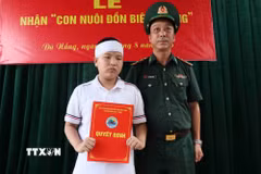 Chỉ huy Tiểu đoàn Huấn luyện-Cơ động, thuộc Ban chỉ huy Bộ đội biên phòng thành phố Đà Nẵng trao Quyết định nhận làm con nuôi cho cháu L.V.H.P. (Ảnh: Đoàn Hữu Trung/TTXVN)