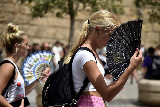 Người dân dưới trời nắng nóng tại Seville (Tây Ban Nha) ngày 13/6/2022. (Ảnh: AFP/TTXVN) Cảnh báo các đợt nóng xảy ra thường xuyên hơn đến những năm 2060 ảnh 1