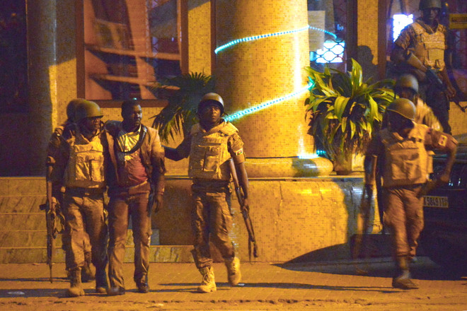 Binh sỹ Burkina Faso đưa một người bị thương rời khỏi khách sạn Splendid. (Nguồn: AFP) Tấn công khủng bố ở Burkina Faso: Đấu súng dữ dội trước khách sạn ảnh 1