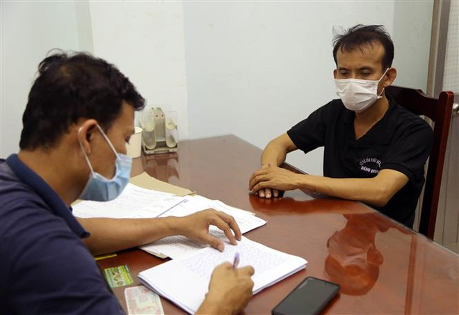 Lấy lời khai của đối tượng đánh bạc đã bị bắt giữ. (Ảnh: Công Thử/TTXVN) Triệt phá đường dây đánh bạc qua mạng quy mô lớn ở Ninh Thuận ảnh 1