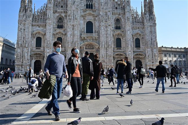 Người dân đeo khẩu trang phòng dịch COVID-19 tại Milan (Italy). (Ảnh: AFP/TTXVN) COVID-19: Quan ngại về làn sóng dịch mùa Đông tấn công châu Âu ảnh 2