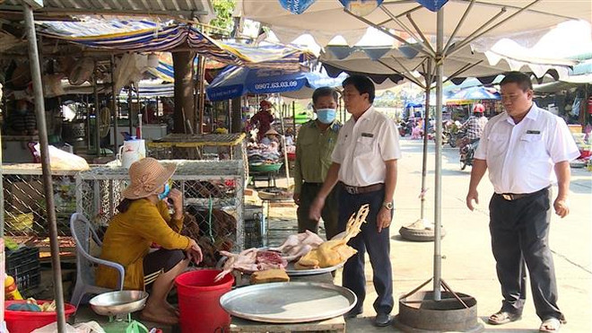 Lực lượng chức năng thị xã Kiến Tường (Long An) kiểm tra mua, bán gia cầm tại khu vực chợ vùng biên giới. (Ảnh: TTXVN phát) Xử lý nghiêm các trường hợp vận chuyển trái phép gia cầm vào Việt Nam ảnh 2