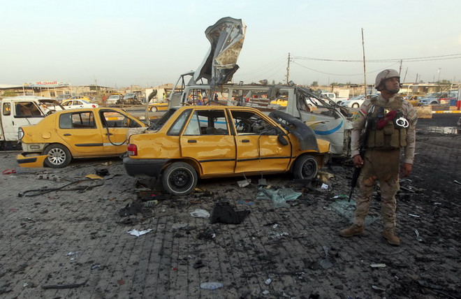 Binh sỹ Iraq điều tra tại hiện trường một vụ đánh bom ở Baghdad. (Nguồn: AFP/TTXVN) Đánh bom hàng loạt ở Iraq, hơn 130 người thương vong ảnh 1