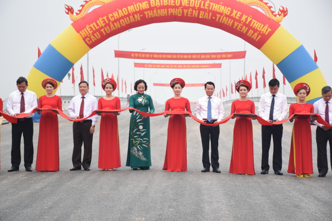Các đại biểu thực hiện nghi thức cắt băng thông xe. (Ảnh: Việt Dũng/TTXVN) Yên Bái thông xe kỹ thuật cầu Tuần Quán kết nối Quốc lộ 32C ảnh 1