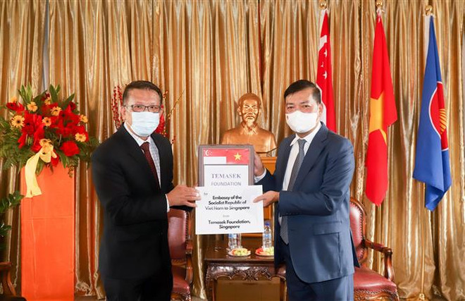 Đại sứ Việt Nam tại Singapore Mai Phước Dũng (phải) tiếp nhấn tượng trưng lô hàng do Quỹ Temasek trao tặng, ngày 16/9/2021. (Ảnh: Lê Dương/TTXVN) Tiếp nhận hàng hỗ trợ Việt Nam chống dịch COVID-19 từ Quỹ Temasek ảnh 1
