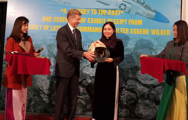Ông Thomas Eugence Wilber trao tặng kỷ vật cho Trưởng Ban quản lý Di tích Nhà tù Hỏa Lò. (Ảnh: Đinh Thuận/TTXVN) Gia đình cựu phi công Mỹ trao tặng hiện vật cho di tích Nhà tù Hỏa Lò ảnh 1