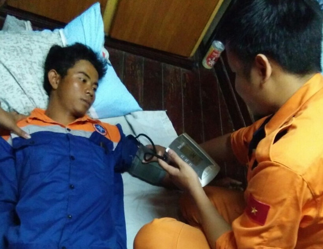 Nhân viên Trung tâm Phối hợp tìm kiếm, cứu nạn hàng hải khu vực IV chăm sóc y tế cho ngư dân gặp nạn. (Ảnh: Phan Sáu/TTXVN) Cứu sống một ngư dân bị mất tích khi đi câu mực trên biển ảnh 1