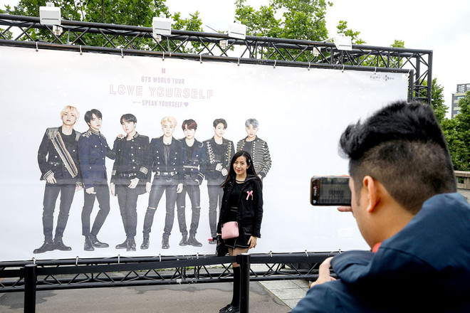 Một phụ nữ chụp ảnh phía trước tấm poster hình ảnh nhóm nhạc BTS bên ngoài sân vận động Stade-de-France, Paris, Pháp. (Nguồn: AFP) Samsung ký kết hợp tác với nhóm nhạc BTS để quảng bá sản phẩm mới ảnh 1