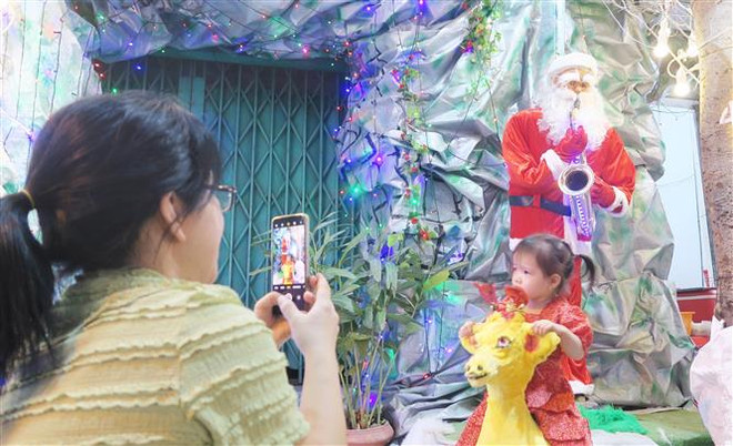 Người dân háo hức chụp ảnh kỷ niệm tại một tiểu cảnh trên đường Phạm Thế Hiển, Quận 8. (Ảnh: Đinh Hằng/TTXVN) hcm-giang-sinh-2-1228.jpg