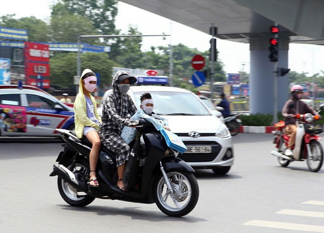 Trang phục bịt kín để chống chọi lại cái nắng gắt của người dân khi tham gia giao thông. (Ảnh: Danh LamTTXVN) Hà Nội: Nhiều người nhập viện điều trị tổn thương da do nắng nóng ảnh 1