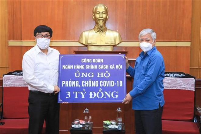 Chủ tịch Ủy ban Trung ương Mặt trận Tổ quốc Việt Nam Đỗ Văn Chiến (phải) tiếp nhận số tiền ủng hộ từ Công đoàn Ngân hàng Chính sách xã hội. (Ảnh: Minh Đức/TTXVN) Quỹ vaccine phòng COVID-19 đã nhận được hơn 8.743 tỷ đồng ảnh 1