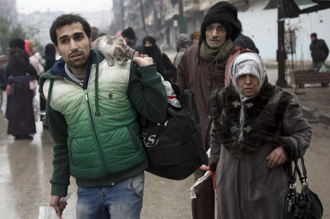 Người dân Syria sơ tán khỏi các khu vực do quân nổi dậy kiểm soát để đến các khu vực đã được quân Chính phủ giải phóng ở Aleppo ngày 13/12. (Nguồn: AFP/TTXVN) Hàng nghìn phiến quân, dân thường rời khỏi phía Đông Aleppo ảnh 1
