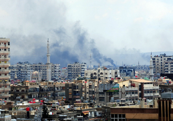Khói bốc lên từ khu vực do phiến quân kiểm soát ở phía nam Damascus sau một cuộc oanh kích của quân đội Syria ngày 22/4. (Nguồn: THX/TTXVN) Tổng thống Syria Assad khẳng định quyết tâm chống khủng bố ảnh 1
