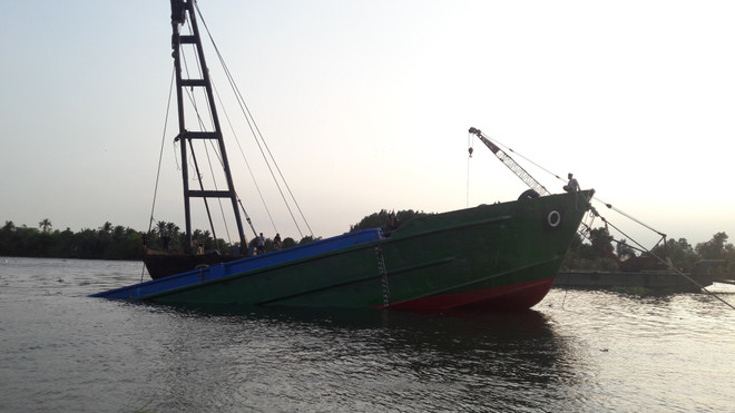 Sà lan đang được lực lượng chức năng trục vớt. (Ảnh: Huyền Trang/TTXVN) Binh Dương: Trục vớt sà lan hàng trăm tấn trên sông Sài Gòn ảnh 1