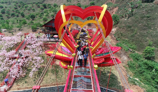 Du khách tham quan và trải nghiệm cầu kính tình yêu tại Khu du lịch sinh thái thác Dải Yếm, huyện Mộc Châu, tỉnh Sơn La. (Nguồn: TTXVN phát) Độc đáo cây cầu kính tình yêu 5D đầu tiên ở Việt Nam ảnh 1