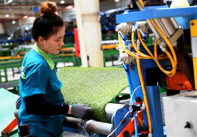 Công nhân làm việc tại một công ty sản xuất thảm cỏ nhân tạo ở khu công nghiệp Phước Đông (tỉnh Tây Ninh). (Ảnh: Hồng Đạt/TTXVN) Hiến kế xây dựng Mộc Bài thành trung tâm thương mại quốc tế ảnh 3