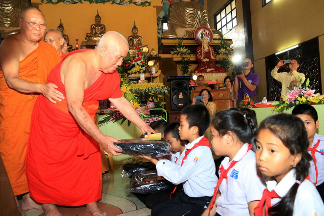 Các nhà sư trao quà cho các học sinh nghèo vượt khó tại buổi lễ. (Ảnh: Phạm Kiên/TTXVN) Cộng đồng người Việt tưởng niệm danh tăng Thích Trung Quán tại Lào ảnh 1