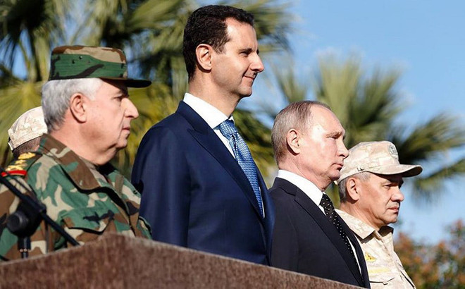 Tổng thống Syria Bashar al-Assad đứng bên cạnh Tổng thống Nga Putin, ngày 11/12 ở căn cứ không quân Nga tại Hmeimim, Syria. (Nguồn: AFP) Tổng thống Assad: Nga đóng vai trò quan trọng trong tái thiết Syria ảnh 1